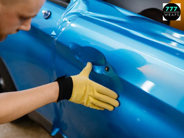 Technician installing gloss blue vinyl car wrap by 777 Wraps in Amarillo TX