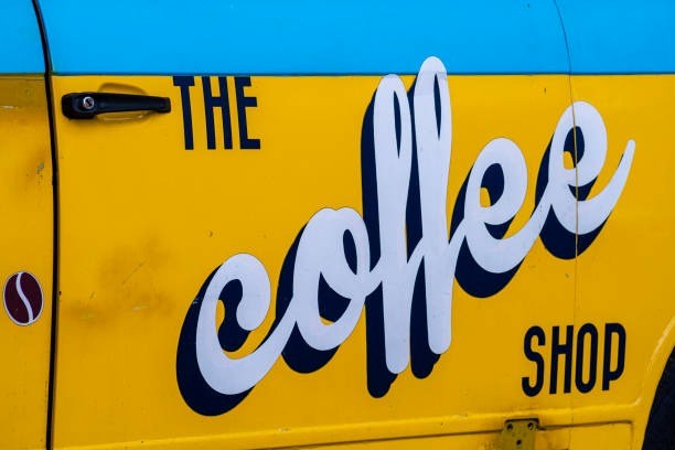 Yellow and blue van with large text representing the business “The Coffee Shop”.